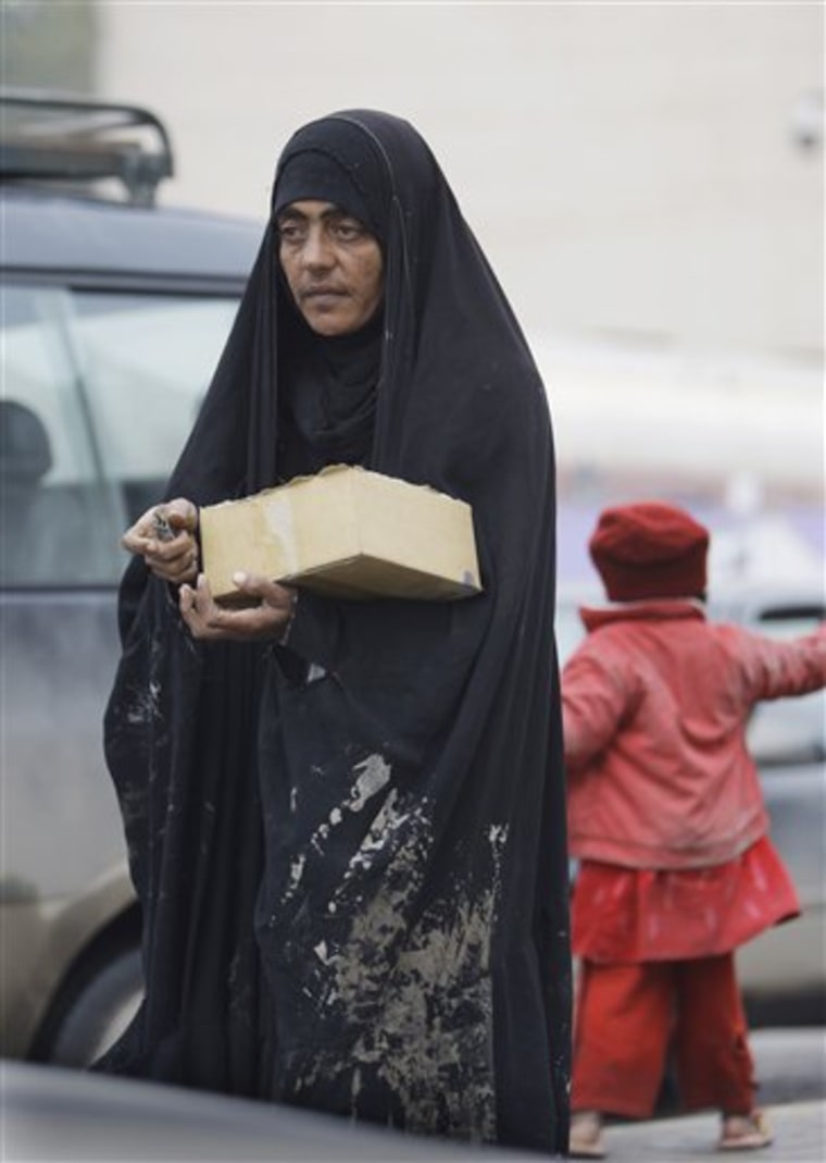 An Iraqi woman and her daughter sell chewing gum in the rain in Baghdad, Iraq, Sunday, Jan. 30.